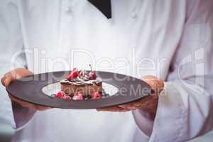 Chef holding a plate with a dessert