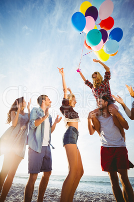 Friends dancing on sand with balloon