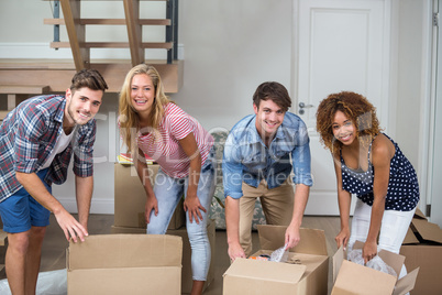 Happy friends unpacking boxes in new house