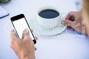 Close up of masculine hands using smartphone and having coffee