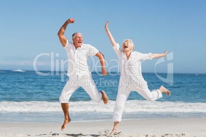 Senior couple jumping at the beach