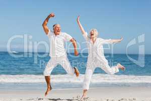 Senior couple jumping at the beach