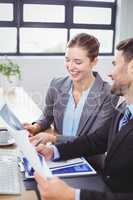 Business people smiling while discussing over documents