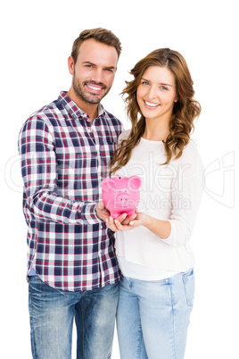 Happy young couple holding piggy bank