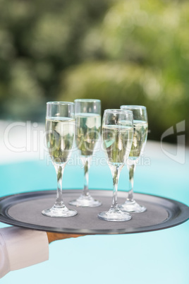 Cropped hands of waiter holding champagne flutes tray