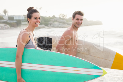 Couple with surfboard running on the beach