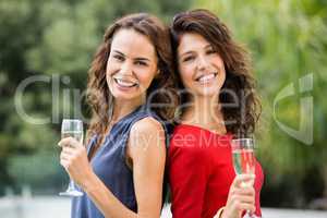 Smiling female friends holding champagne flutes