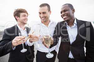 Well dressed men drinking champagne next to a limousine