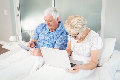 Senior couple using technologies on bed