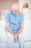 Thoughtful senior man sitting on bed