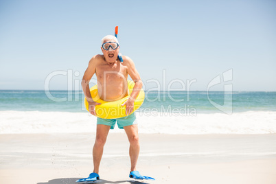 Senior man with swimming ring and flippers at the beach