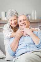 Smiling senior couple hugging while sitting on sofa