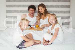 Portrait of siblings with parents on bed