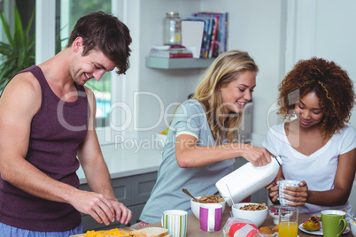 Smiling woman pouring milk at table