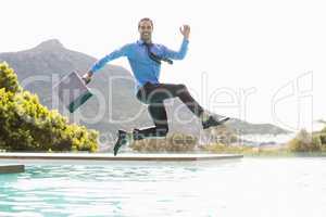 Businessman jumping over swimming pool