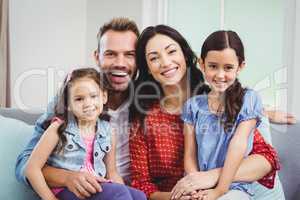 Portrait of cheerful parents sitting with daughters
