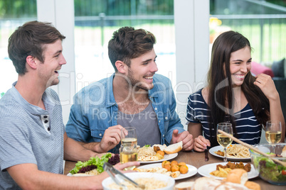 Friends smiling while having meal at table