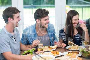 Friends smiling while having meal at table