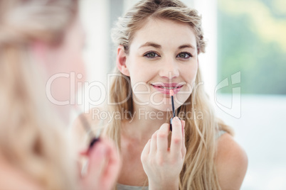 Portrait of smiling young woman applying lip gloss