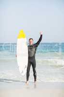 Happy man holding a surfboard on the beach