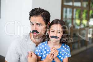 Portrait of father and daughter with artificial mustache