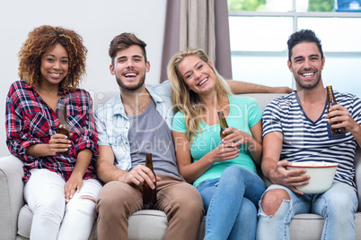 Multi-ethnic young friends enjoying beer on sofa