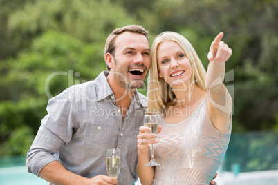 Woman pointing while standing by man holding champagne flute
