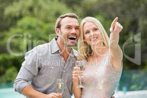 Woman pointing while standing by man holding champagne flute