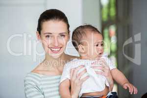 Portrait of cheerful mother carrying baby