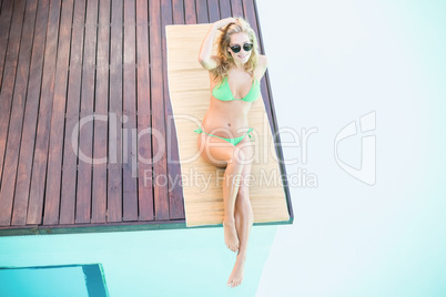 Beautiful woman in green bikini relaxing by pool side