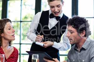 Young waitress taking an order from a couple