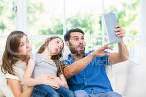 Family making face while clicking selfie with digital table
