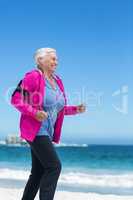 Focused mature woman running and listening to music