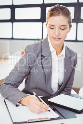 Beautiful businesswoman writing in notepad