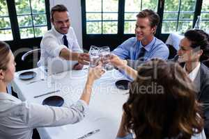 Group of businesspeople toasting glass of water in restaurant