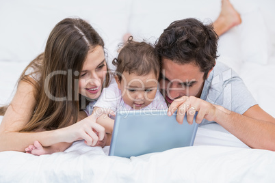 Family looking at digital tablet on bed