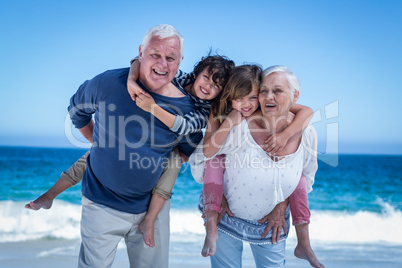 Happy grandparents giving piggy back to children