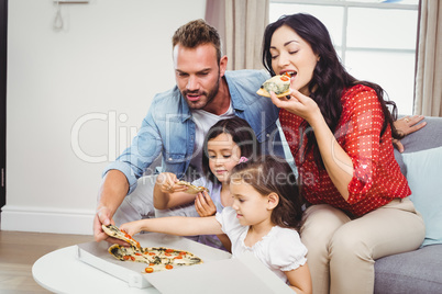 Family of four eating pizza at home