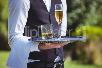 Handsome waiter holding a tray with drinks