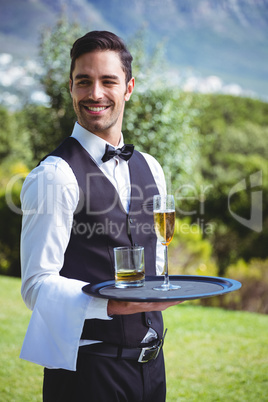 Handsome waiter holding a tray with drinks