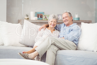 Portrait of romantic senior couple sitting on sofa in living roo