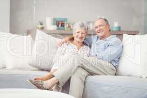 Portrait of romantic senior couple sitting on sofa in living roo