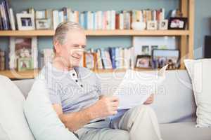 Happy senior man reading newspaper