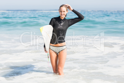 Happy woman with surfboard standing in water