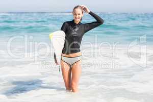 Happy woman with surfboard standing in water