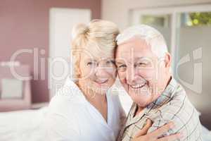 Portrait of happy couple embracing in bedroom