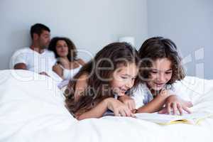 Brother and sister reading book together on bed