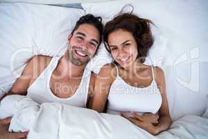 Portrait of smiling couple relaxing on bed