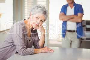 Portrait of worried senior woman with man standing in background