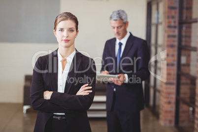 Confident businesswoman with male colleague in background